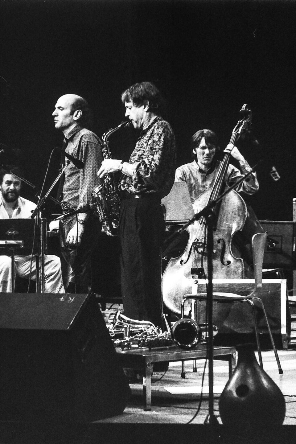 Bühne beim Jazzfestival Amiens, Frankreich, Mai 1987: vorn zwei Saxophonisten und der Kontrabass, links sitzend Harry Pepl mit der Gitarre. Laut Besetzung von „Men's Land“ spielten Michel Portal, Dave Liebman und Jean-François Jenny-Clark.